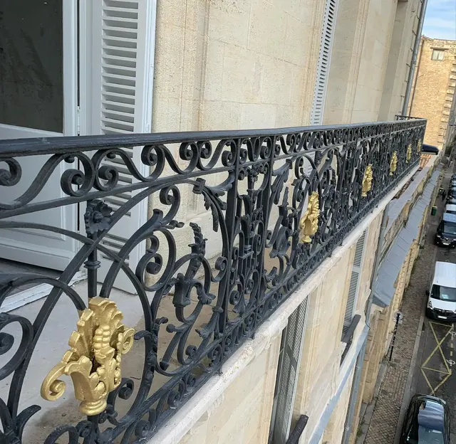Balcon filant en fer forgé aux ornements dorés